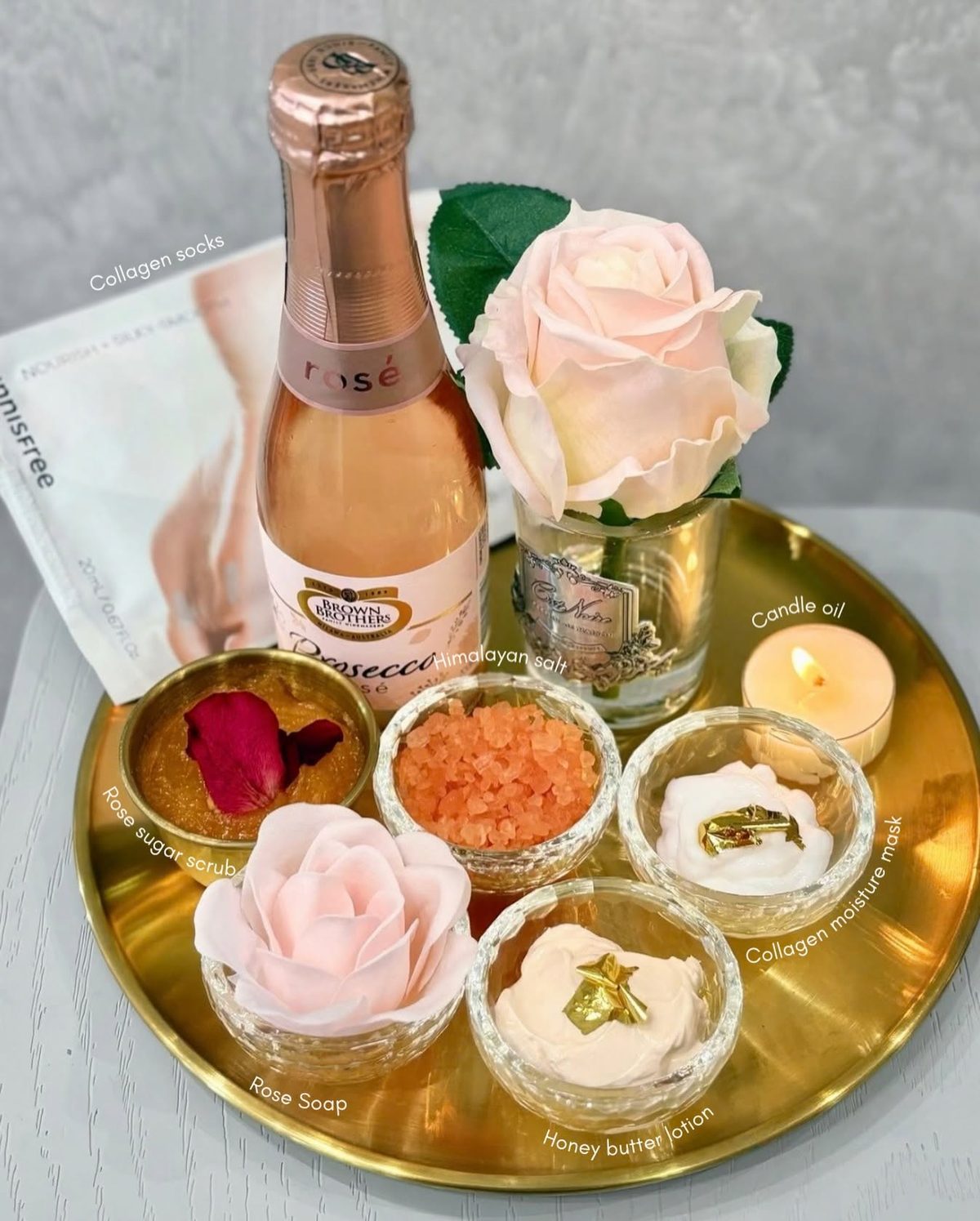 Rosé, roses and pedicure treatments arranged on a gold tray